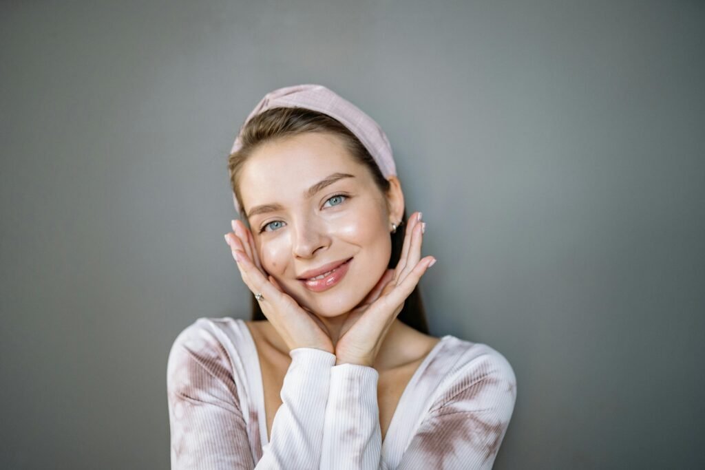 Portrait of a smiling woman with a headband against a gray background.